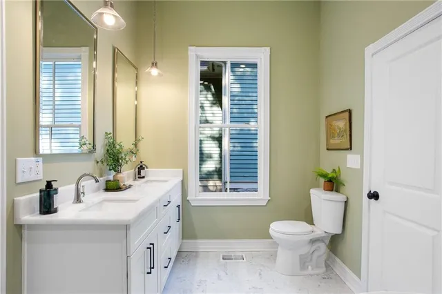 a bathroom with a granite countertop toilet sink and mirror