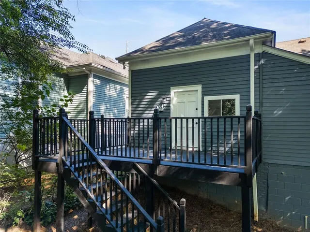 a view of a house with wooden deck and a forest