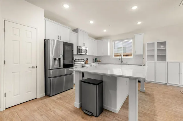 a kitchen with kitchen island a sink stainless steel appliances and refrigerator