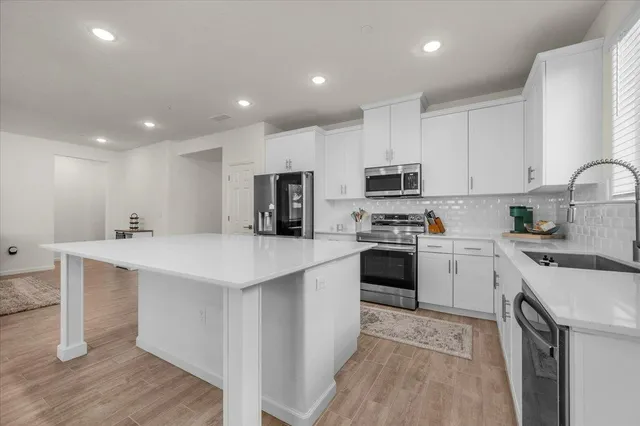 a kitchen with a sink white cabinets and stainless steel appliances