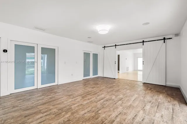 a view of an empty room with wooden floor and a bathroom