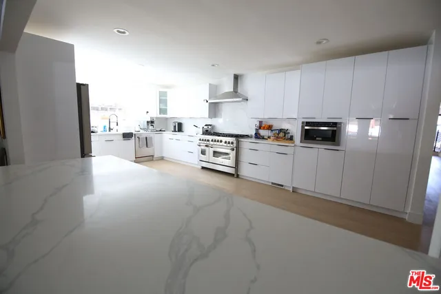 a kitchen with stainless steel appliances a refrigerator a stove a sink and white cabinets