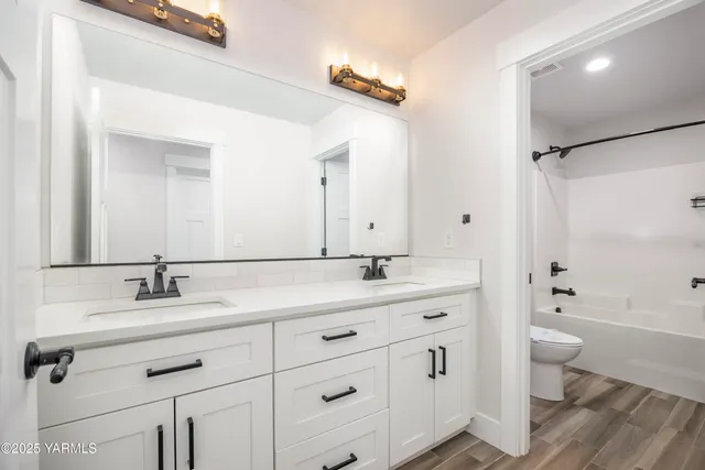 a bathroom with a double vanity sink a toilet and a mirror