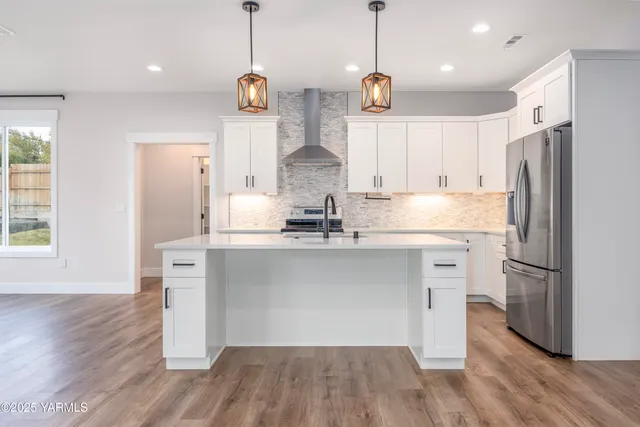 a kitchen with kitchen island white cabinets stainless steel appliances and wooden floor