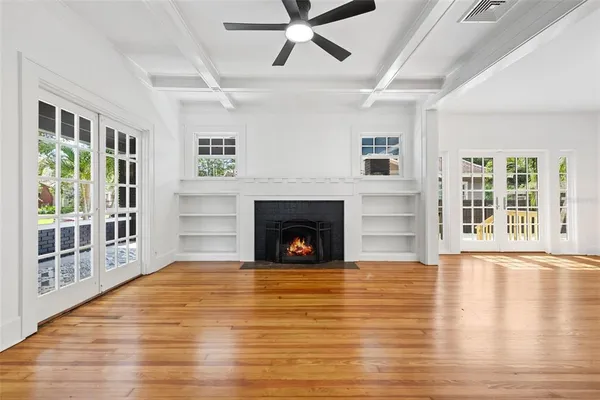 a view of a livingroom with a fireplace a ceiling fan and windows