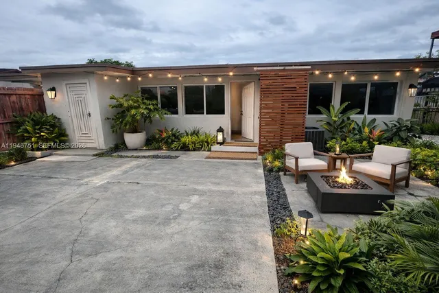 a view of a patio with table and chairs potted plants and floor to ceiling window