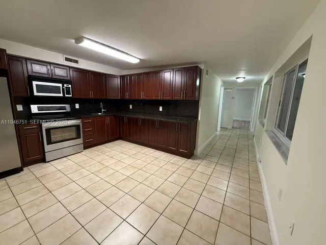 a large white kitchen with a sink and dishwasher a stove with wooden floor