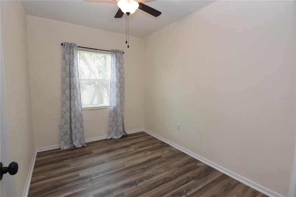 21572 Edgewater Drive Port Charlotte, FL 33952 - Photo 11 of 15 an empty room with wooden floor chandelier fan and windows