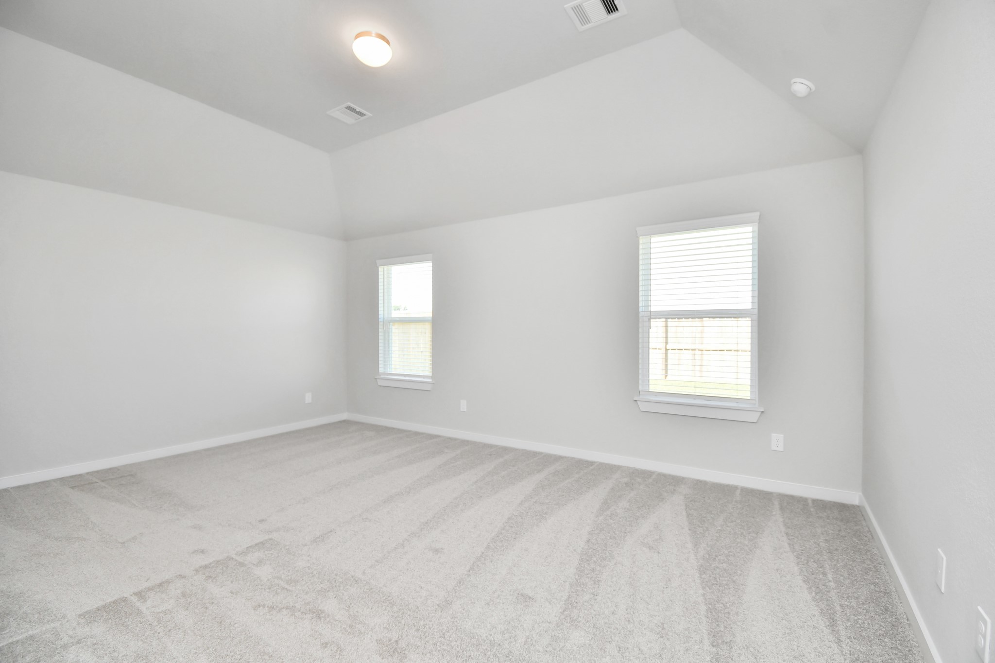 14619 Diamond Dove Lane Houston, TX 77049 - Photo 23 of 33 Retreat to the luxurious primary suite, your perfect escape for unwinding after a long day. Located on the first floor, this spacious room features plush carpeting, calming paint tones, high ceilings, and large windows with privacy blinds. Sample photo of completed home with similar floor plan. Actual colors and selections may vary.