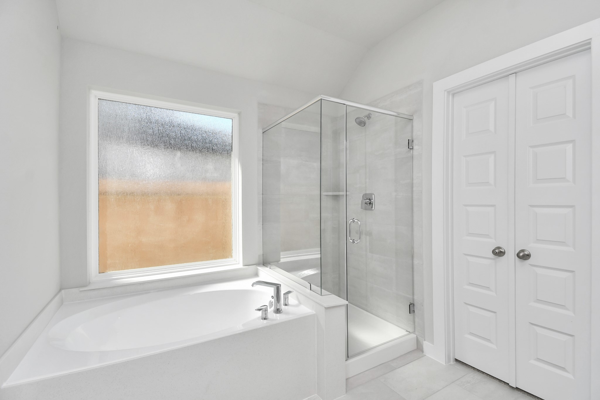 14619 Diamond Dove Lane Houston, TX 77049 - Photo 24 of 33 Escape to a spa-like oasis in this primary bathroom. Enjoy a walk-in shower with tile surround, a separate garden tub with custom detailing, and an elegant vanity featuring light countertops, modern hardware, and beautiful recessed lights. Experience luxury and relaxation in every detail. Sample photo of completed home with similar floor plan. Actual colors and selections may vary.