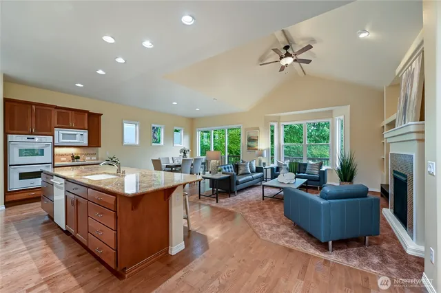 a living room with stainless steel appliances granite countertop furniture sink and wooden floor