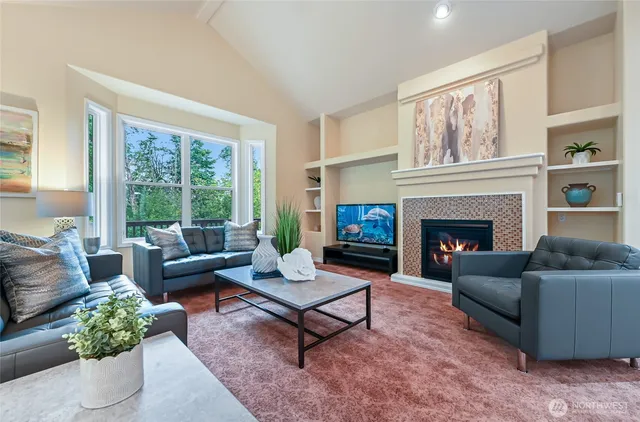 a living room with furniture a rug a fireplace and a large window