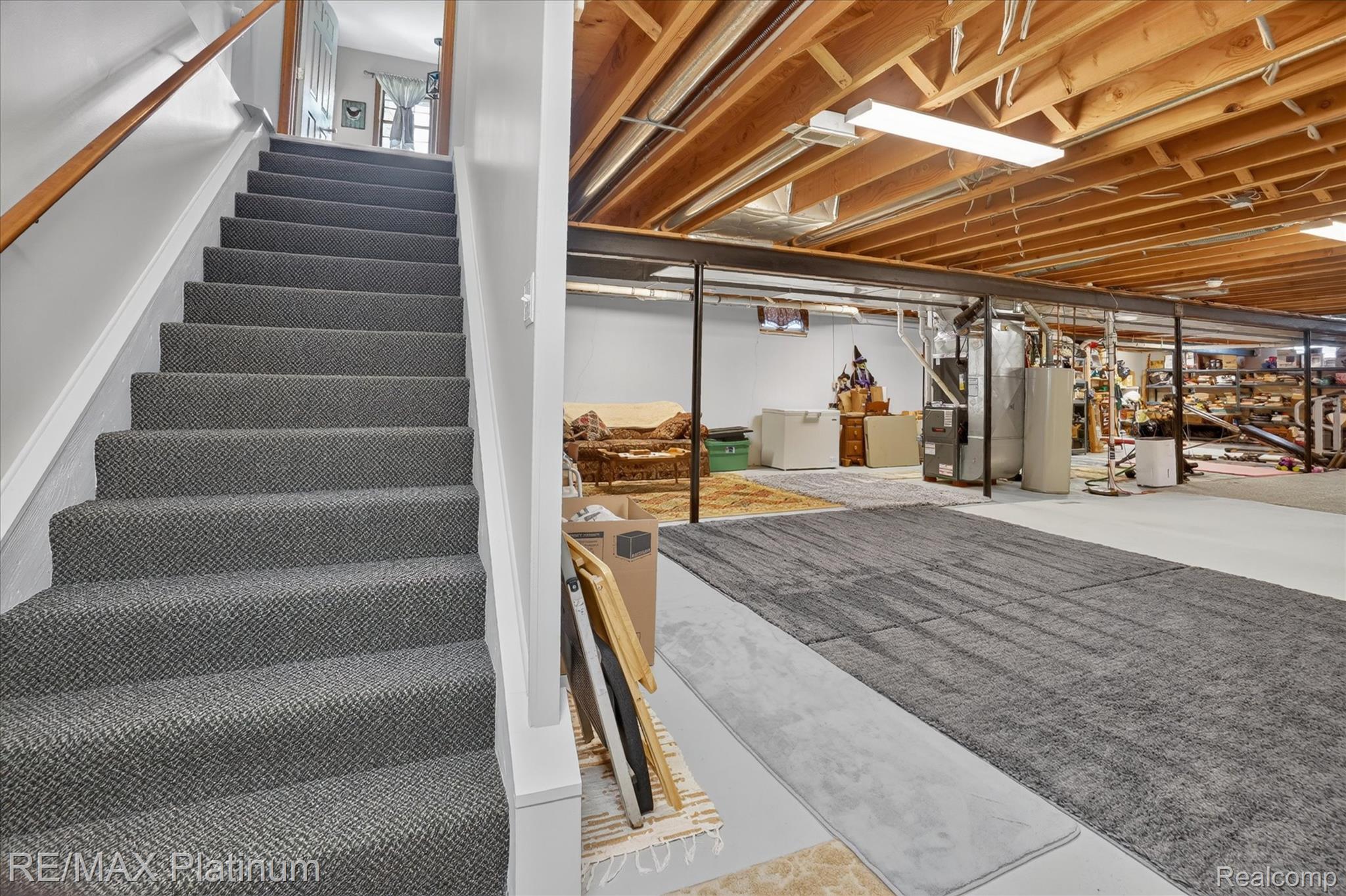 4457 Bradley Road Gregory, MI 48137 - Photo 43 of 79 Carpeted staircase with wood handrail, exposed wood ceiling joists, and concrete flooring
