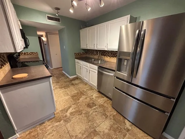 a kitchen with granite countertop a refrigerator and a sink