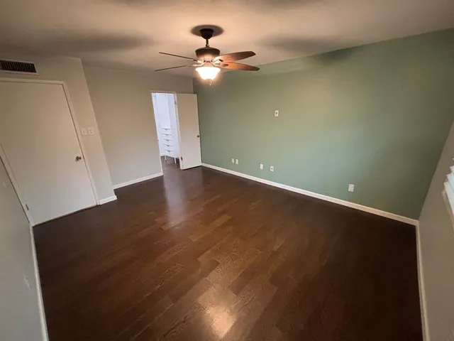 an empty room with wooden floor and fan