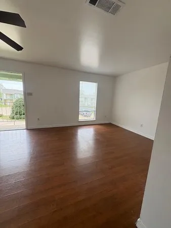 an empty room with wooden floor and windows