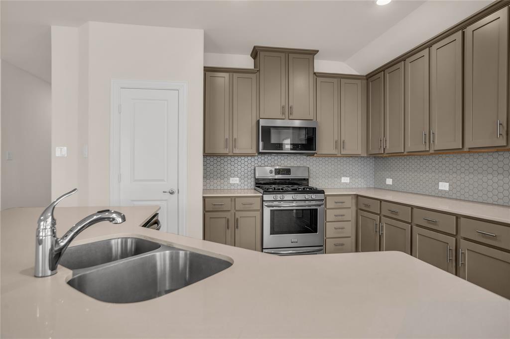 3616 Pinto Way Aubrey, TX 76227 - Photo 21 of 38 a kitchen with stainless steel appliances granite countertop a sink and a stove top oven