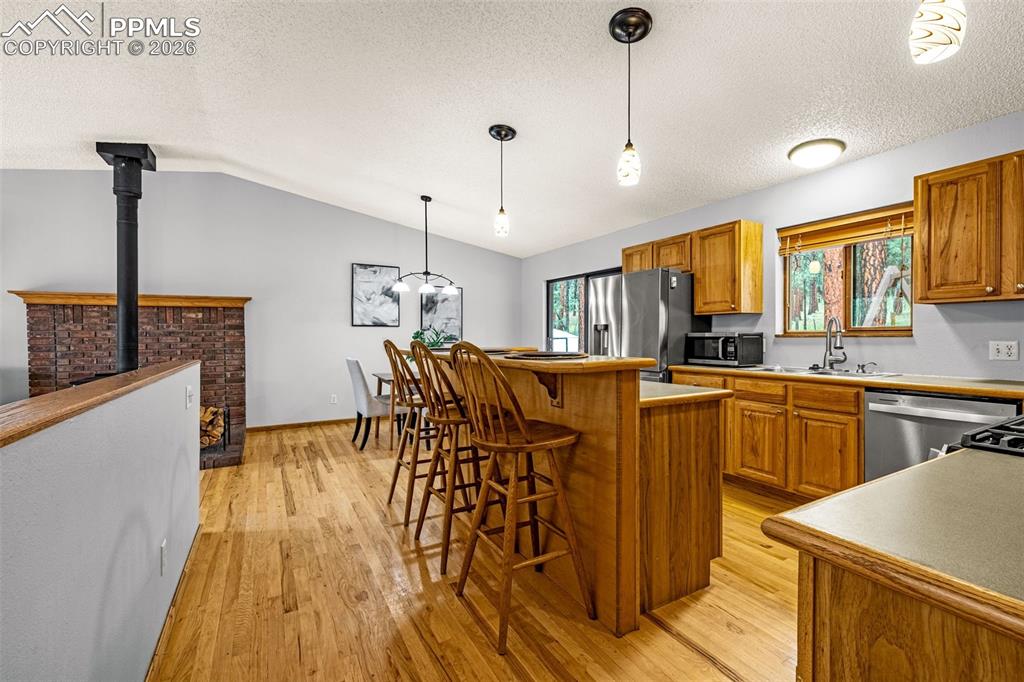 15845 Roller Coaster Road Colorado Springs, CO 80921 - Photo 8 of 29 a kitchen with stainless steel appliances granite countertop a kitchen island a stove a sink a dining table and chairs with wooden floor