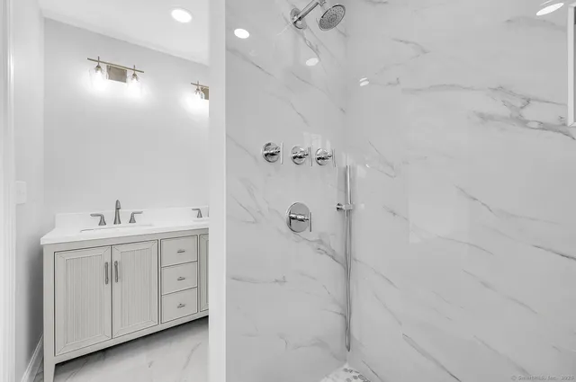 a bathroom with a double vanity sink a toilet and shower