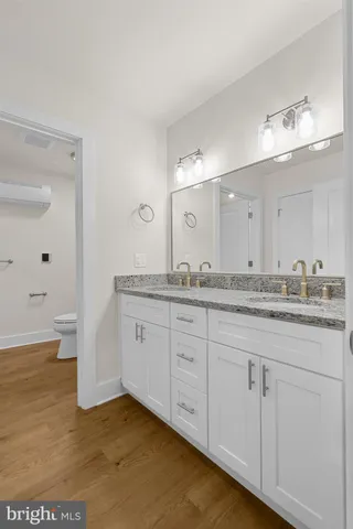 a bathroom with a granite countertop sink a toilet and a mirror