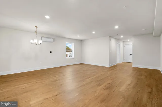 an empty room with wooden floor cabinet and windows
