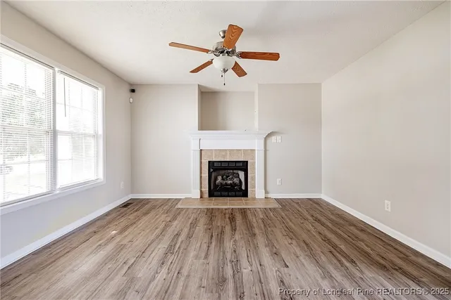 a view of an empty room with wooden floor fireplace and a window