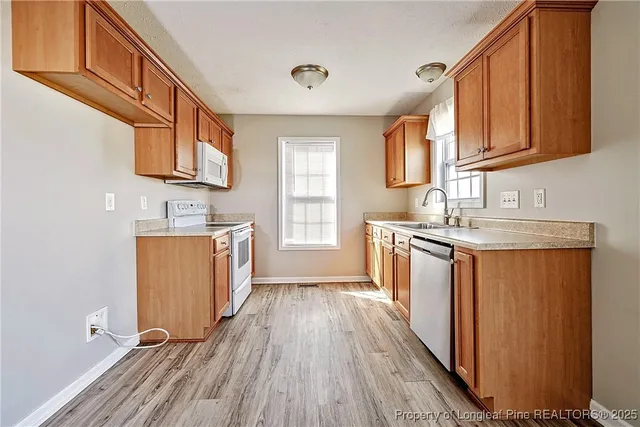 a kitchen with granite countertop wooden floors a sink and appliances