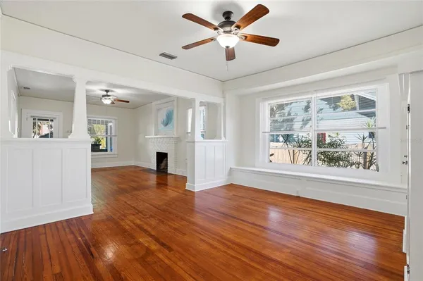 a view of an empty room with window and wooden floor