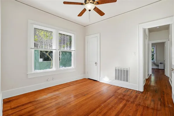 a view of empty room with wooden floor and fan