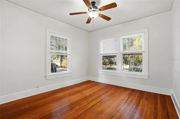 a view of an empty room with wooden floor and a window