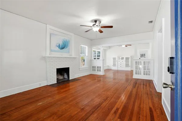 a view of empty room with wooden floor and fireplace