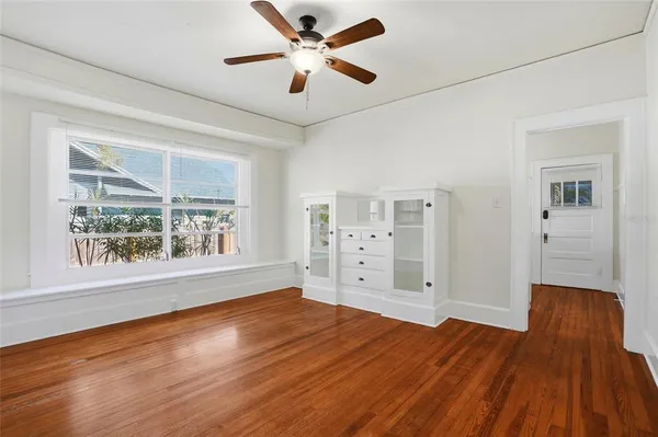 a view of empty room with wooden floor and fan