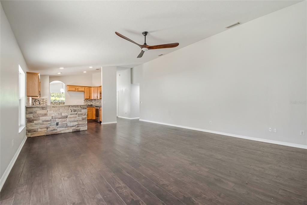 221 Rosa Avenue Oviedo, FL 32765 - Photo 15 of 36 an empty room with wooden floor and a kitchen