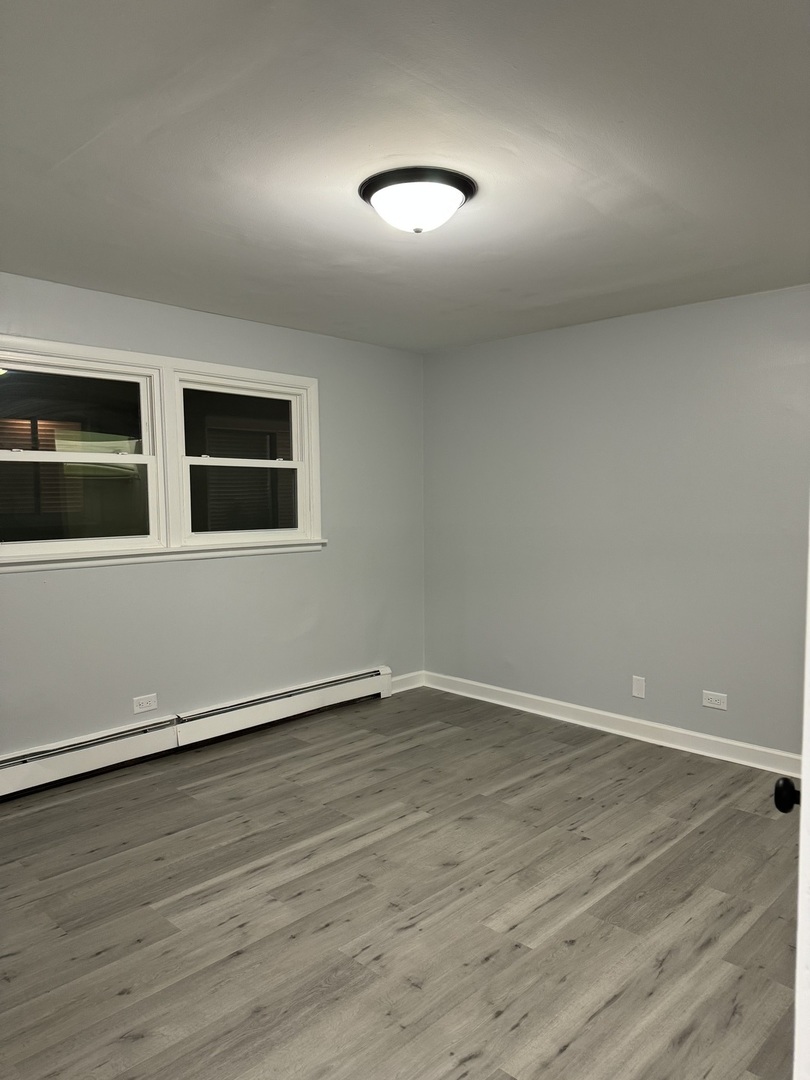 82 Luella Avenue, Unit 2 Calumet City, IL 60409 - Photo 8 of 12 a view of an empty room with wooden floor and a window