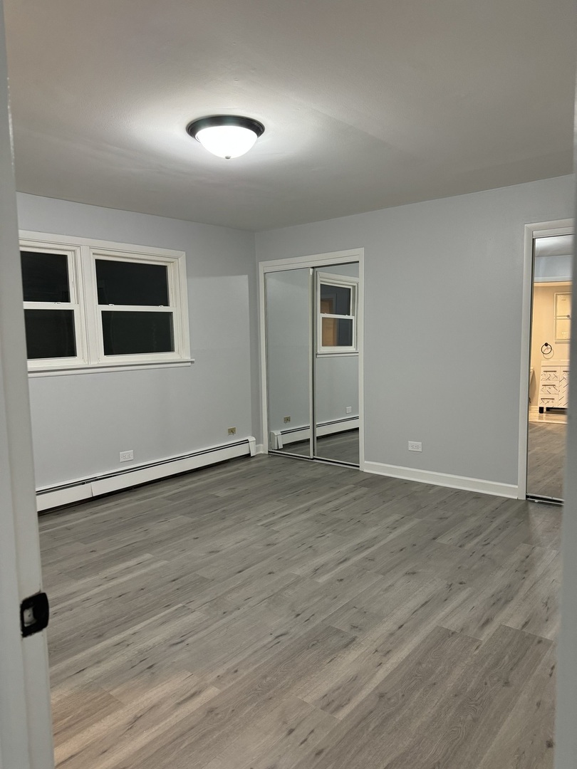 82 Luella Avenue, Unit 2 Calumet City, IL 60409 - Photo 10 of 12 an empty room with wooden floor and windows