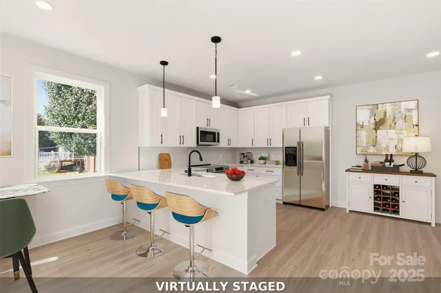 a kitchen with stainless steel appliances a dining table chairs stove refrigerator and cabinets