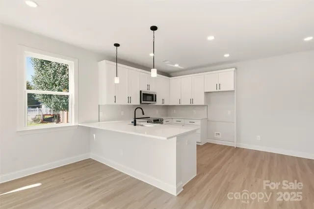 a kitchen with stainless steel appliances granite countertop a sink a stove a refrigerator and island with wooden floor
