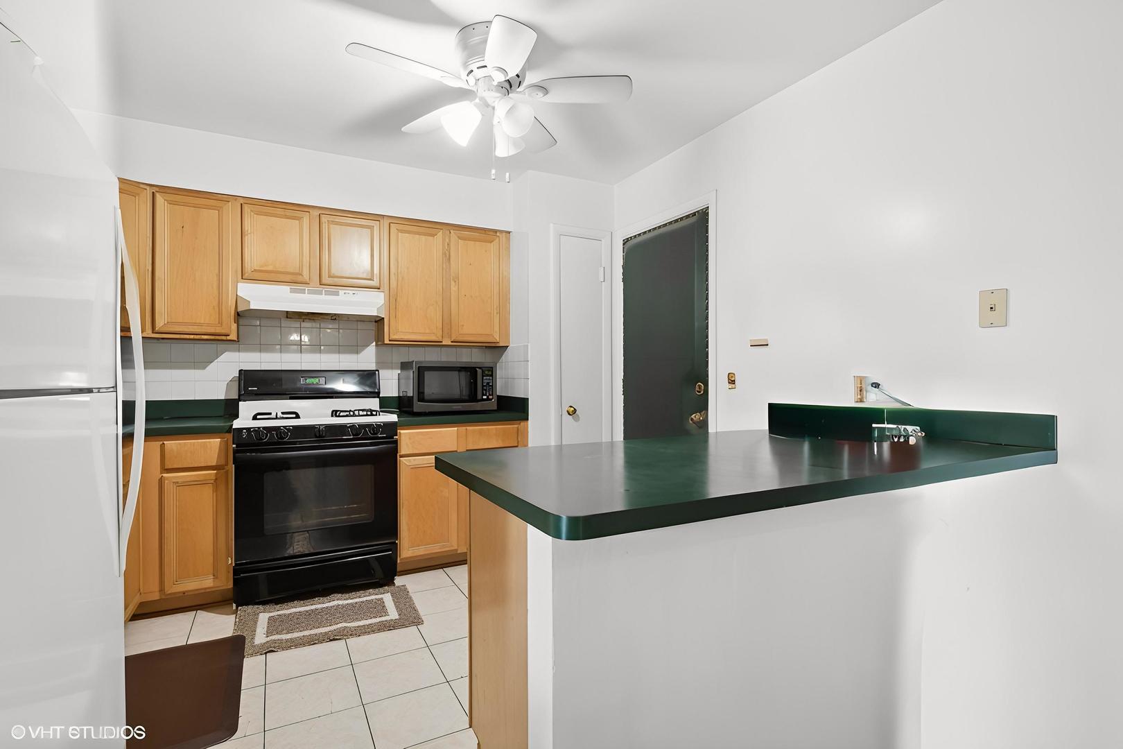 9561 Dee Road, Unit 2G Des Plaines, IL 60016 - Photo 9 of 18 a kitchen with stainless steel appliances granite countertop a sink a stove and a microwave