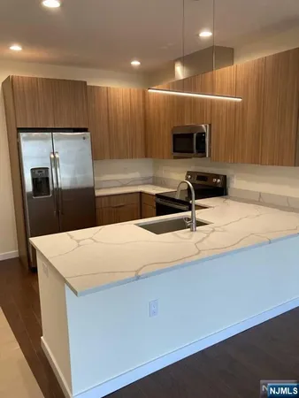 a kitchen with kitchen island a counter a sink and a stove top oven with wooden floor