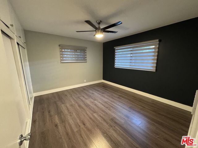 an empty room with wooden floor cabinet and windows