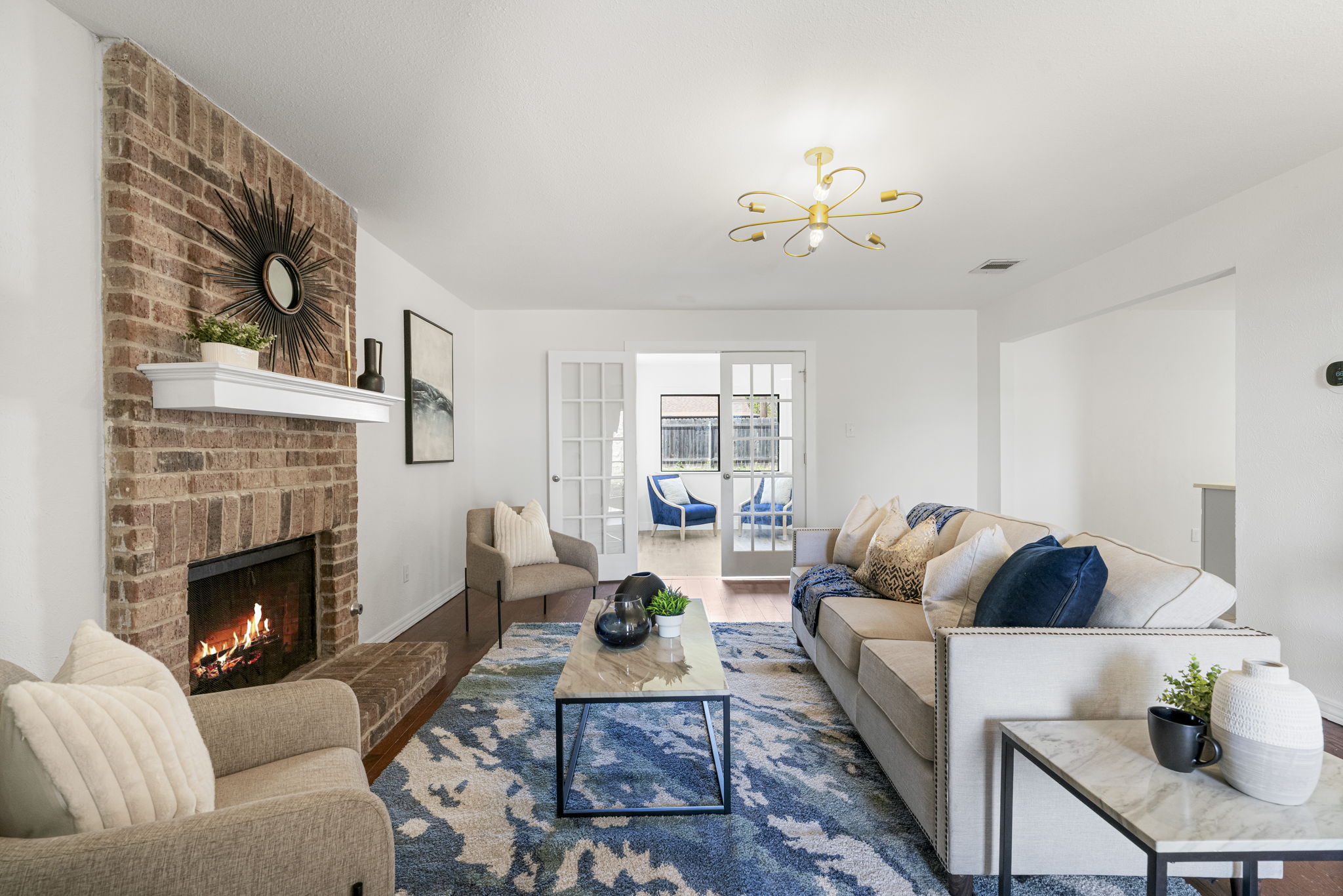 13004 Esplanade Street Austin, TX 78727 - Photo 2 of 36 Living room with a brick fireplace, wood finished floors, and a chandelier