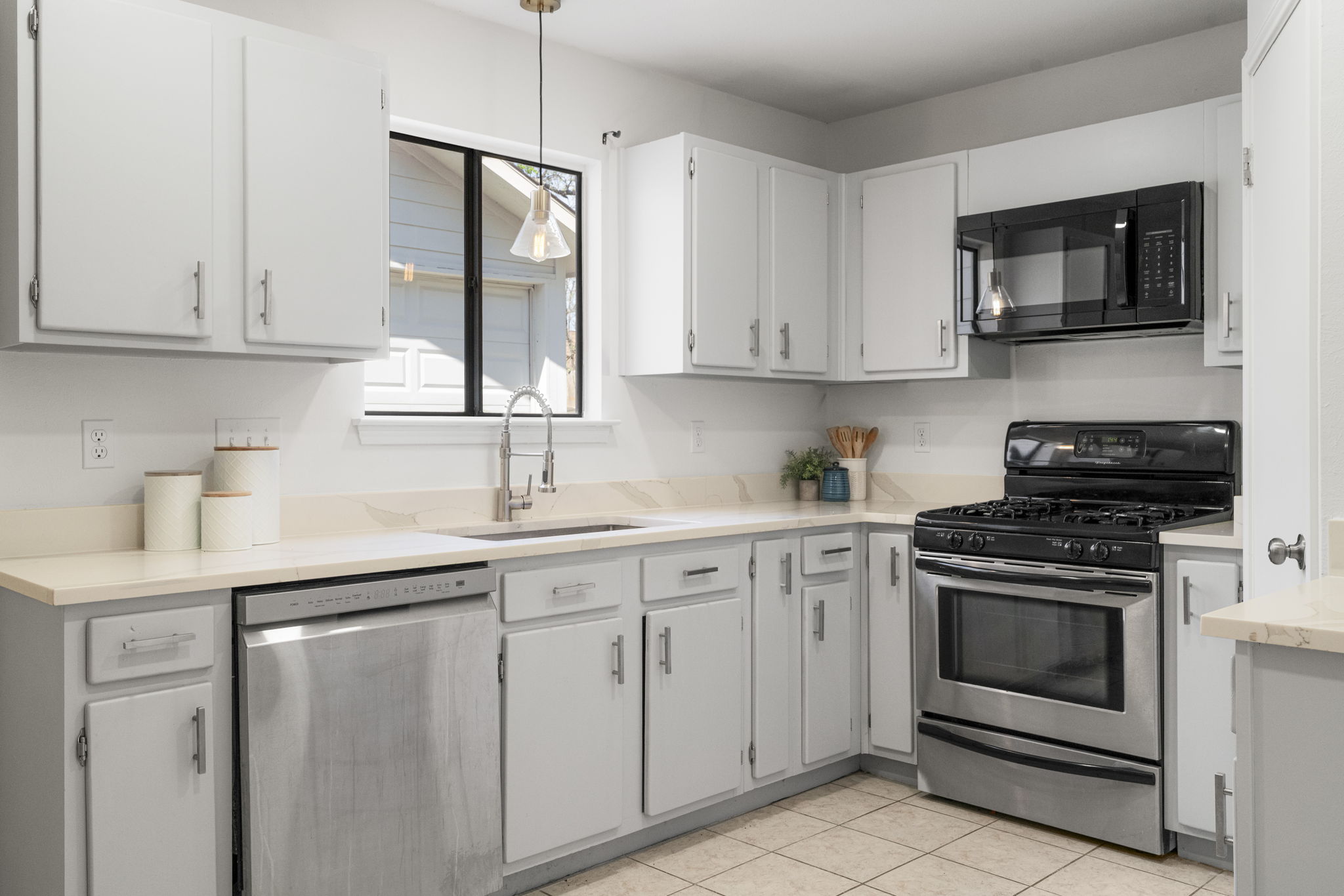 13004 Esplanade Street Austin, TX 78727 - Photo 23 of 36 Kitchen with stainless steel appliances, white cabinetry, light tile patterned flooring, and pendant lighting