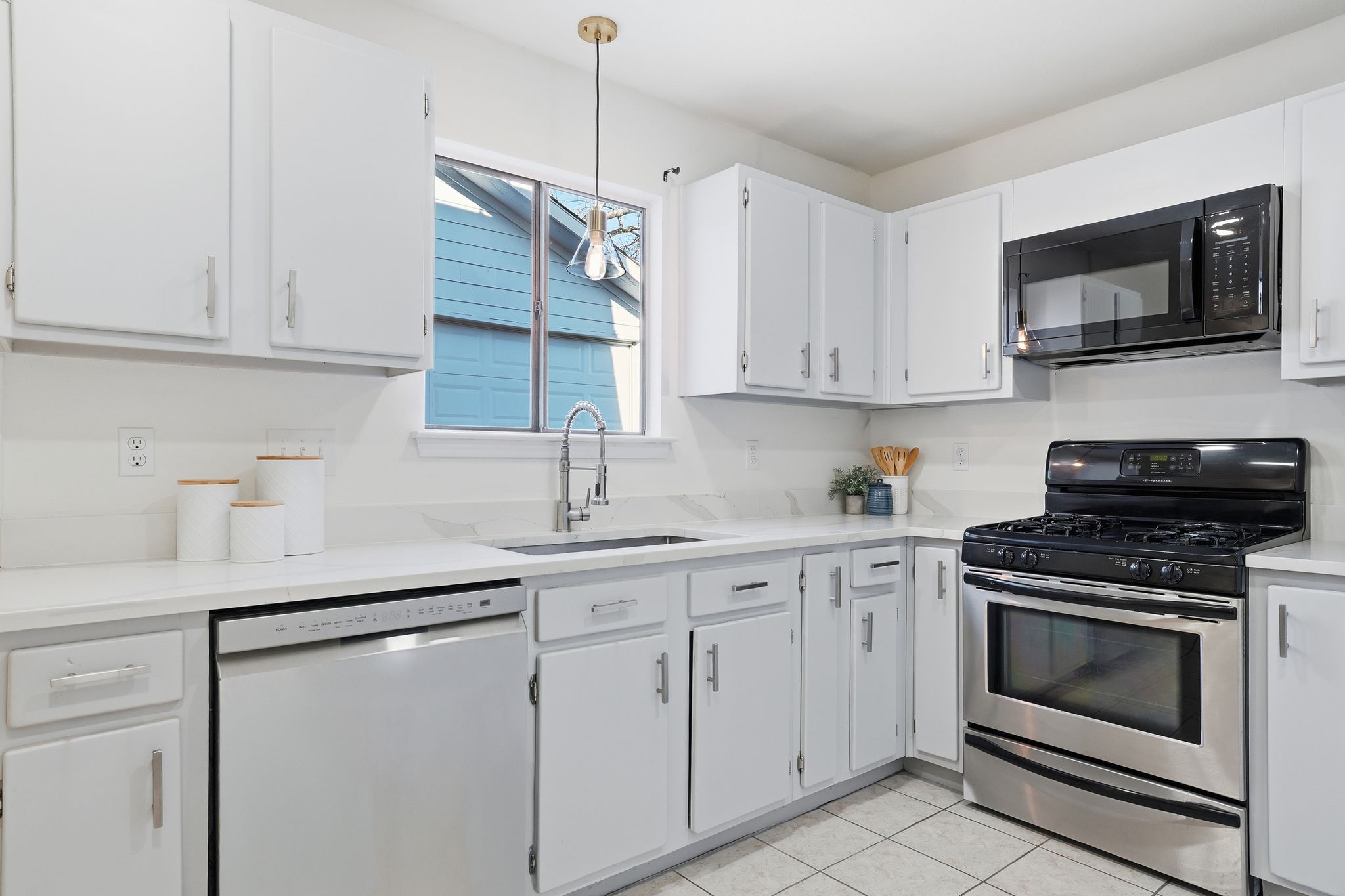 13004 Esplanade Street Austin, TX 78727 - Photo 4 of 36 Kitchen featuring stainless steel range with gas stovetop, black microwave, dishwasher, and white cabinetry