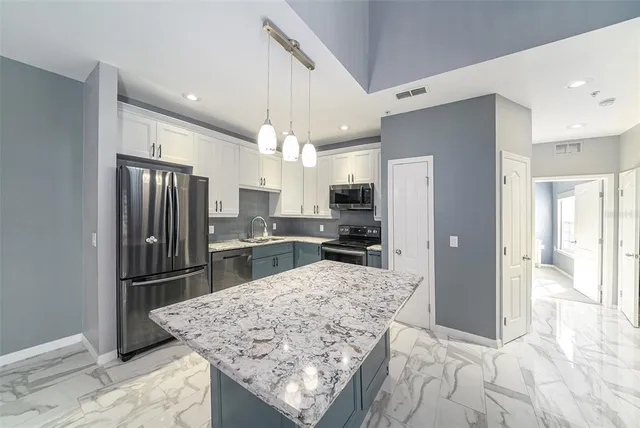 a kitchen with stainless steel appliances kitchen island granite countertop a refrigerator and microwave