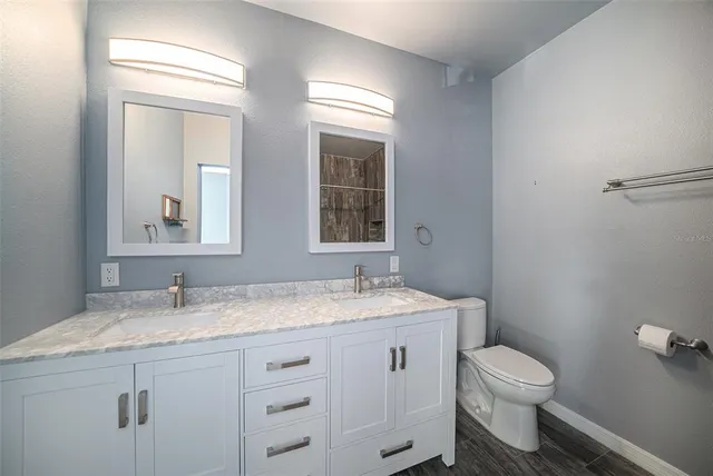 a bathroom with a granite countertop toilet sink and mirror