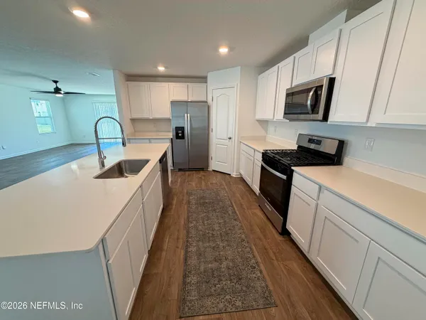 a kitchen with stainless steel appliances granite countertop a sink dishwasher a refrigerator and a stove with wooden floor