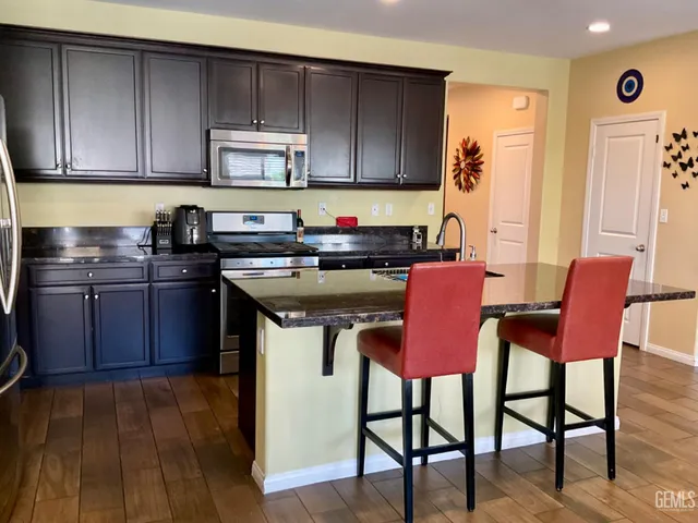 a kitchen with stainless steel appliances granite countertop a stove top oven a sink and a chairs