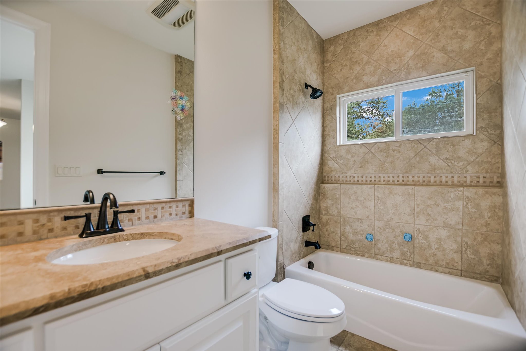11 Inwood Circle Austin, TX 78746 - Photo 28 of 38 A well-appointed bathroom features a shower-tub combination, tile surround, and a vanity with a generous mirror.