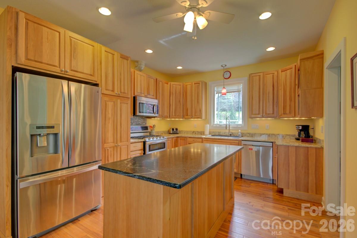 751 Everett Road Pisgah Forest, NC 28768 - Photo 4 of 36 a kitchen with stainless steel appliances granite countertop a refrigerator a sink dishwasher a stove and a refrigerator with wooden floor