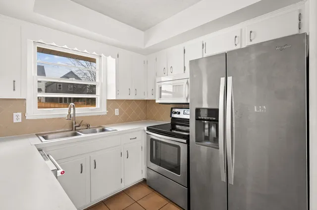 a kitchen with a sink a refrigerator a window and cabinets